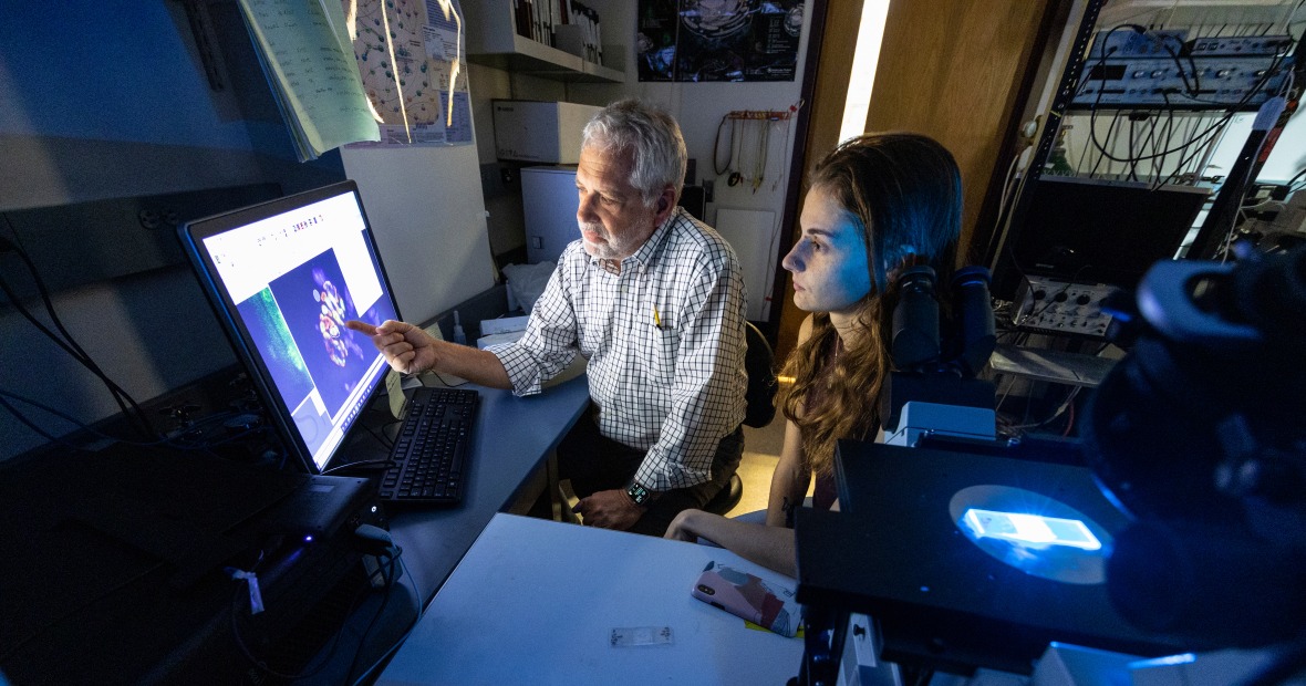 Professor Clark Lindgren and a student researcher looking at an image from the microscope on a computer screen.